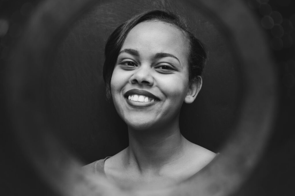 Black and white portrait of a woman with a warm smile, framed with a circular blur.